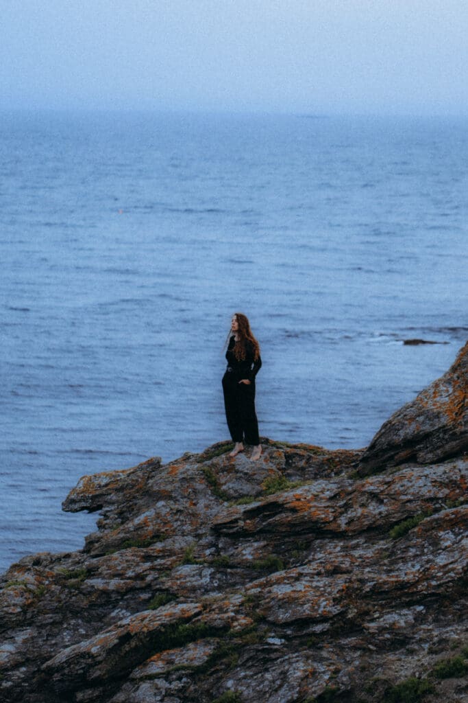 Silhouette de femme debout sur les rochers face à la mer, photographie portrait artistique