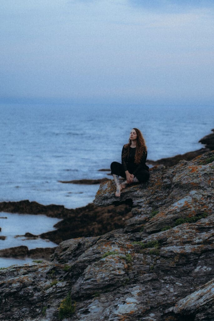 Photographe assise sur les rochers, contemplant la mer, portrait intimiste