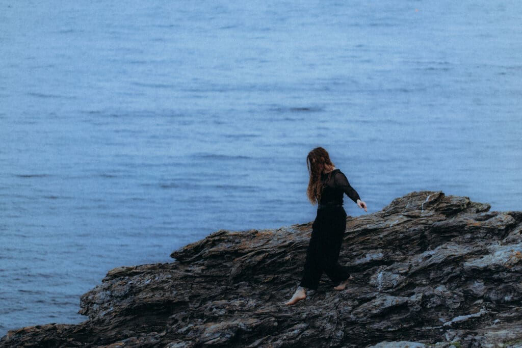Femme debout sur les rochers en bord de mer, lumière naturelle, territoire côtier