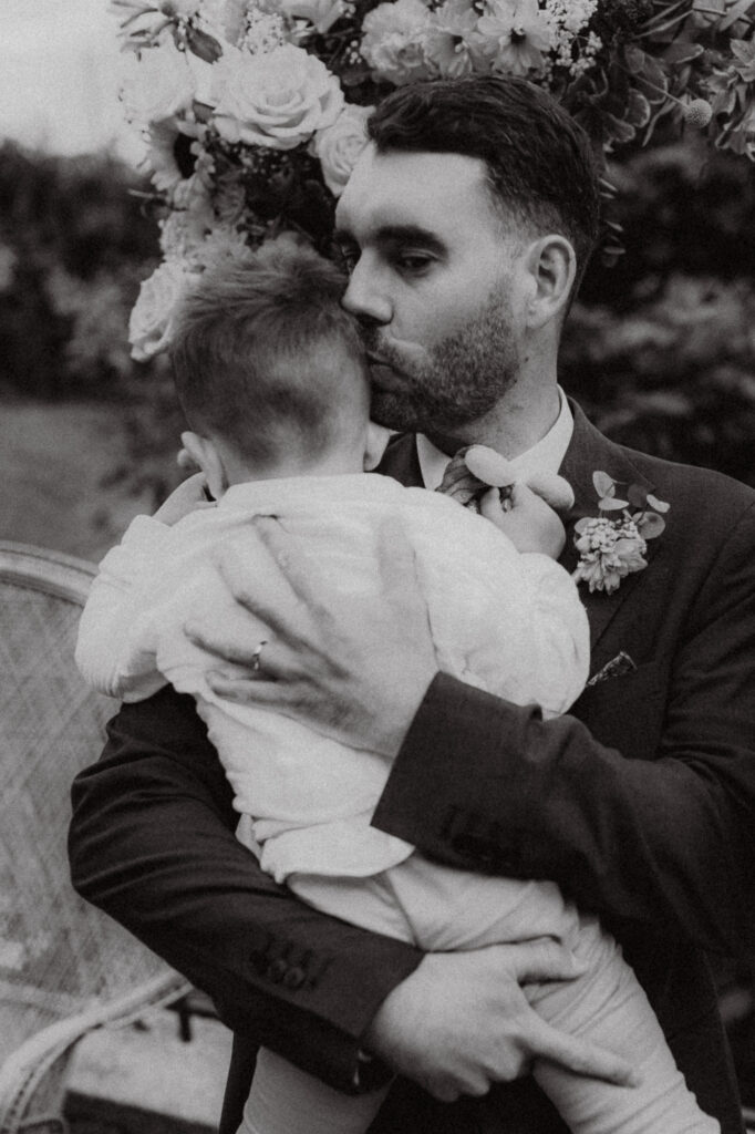 Un père embrassant son fils rempli d'émotion après la cérémonie laïque de leur mariage