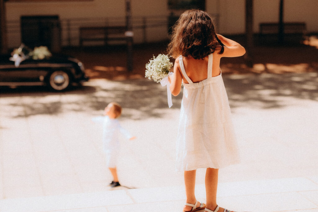 Petite fille en robe blanche dans un jardin, moment de vie lors d'un mariage
