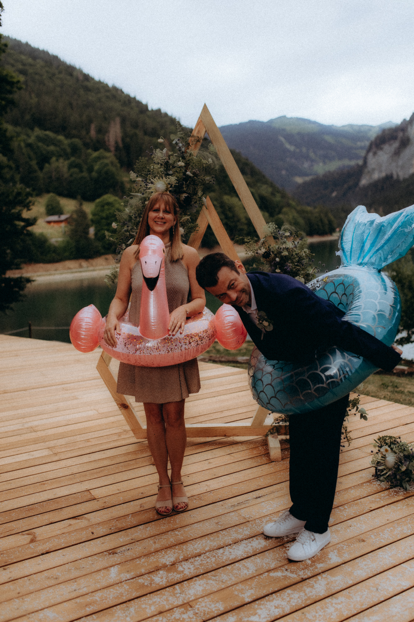 Couple qui pose avec des bouées gonflables devant un lac de montagne
