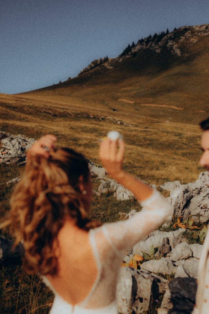 Mariée qui lance des fleurs de coton en altitude, lumière dorée, Chartreuse