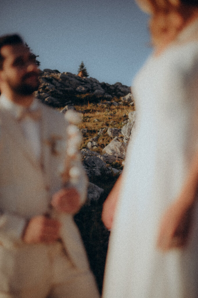 Gros plan fleurs de coton tenues par le marié, détail poétique séance anniversaire