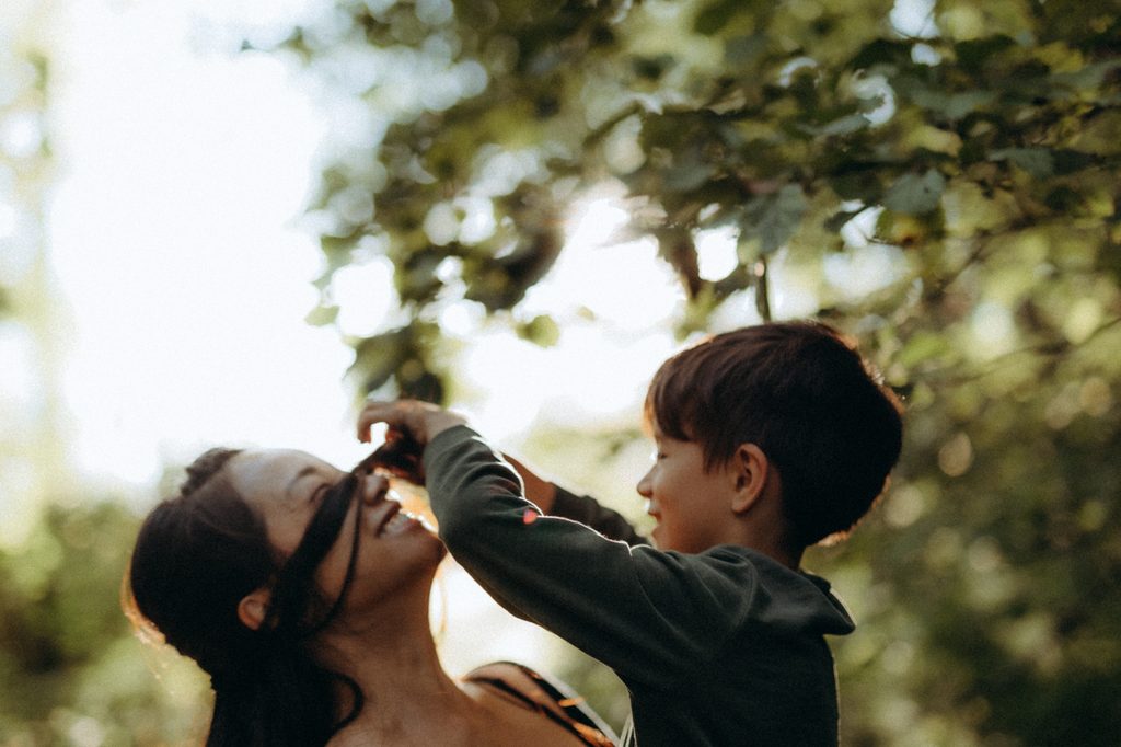 Glenn qui joue avec les cheveux de Jen, jeu complice mère et fils, séance photo famille en plein air