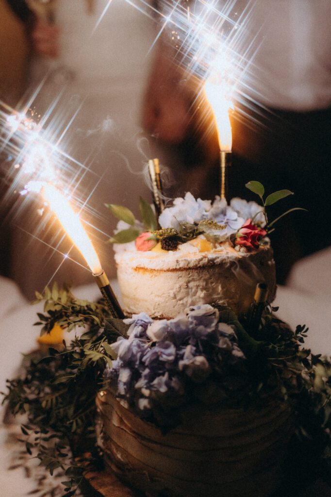Gâteau de mariage fleuri avec bougies étincelantes