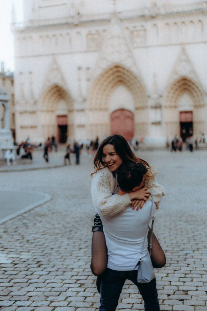Couple qui rit sur le parvis de la cathédrale Saint-Jean, love session à Lyon