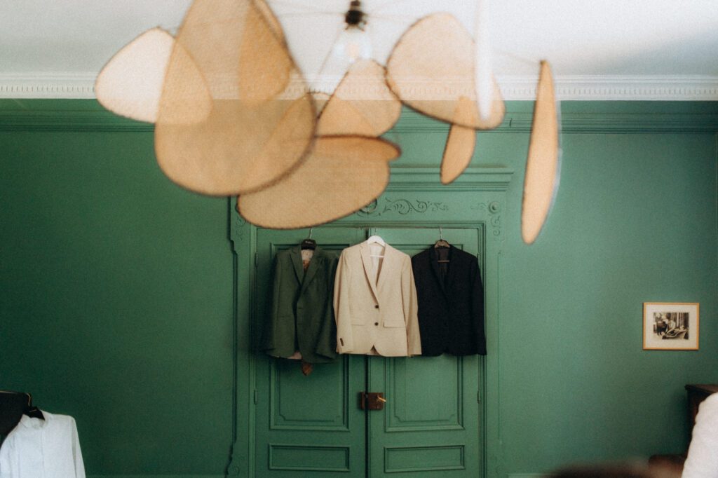 Costumes des mariés et des témoins suspendus à un mur vert, préparatifs