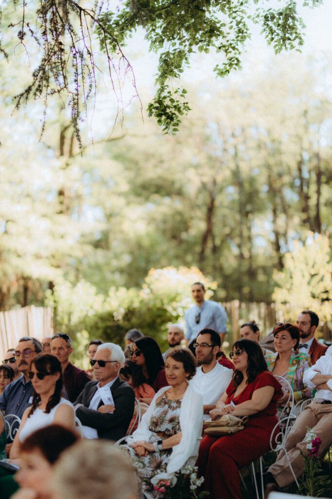 Invités assis dans l'herbe sous les arbres pendant la cérémonie laïque