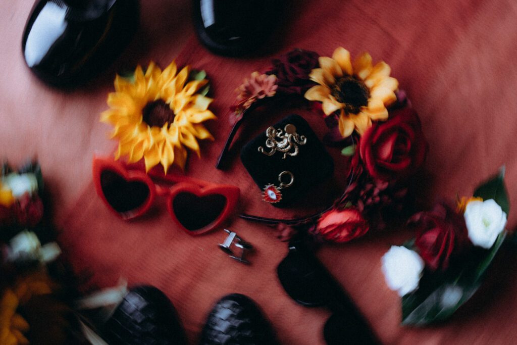 Tournesols, roses rouges et lunettes en forme de cœur sur un tissu rouge, détails de mariage