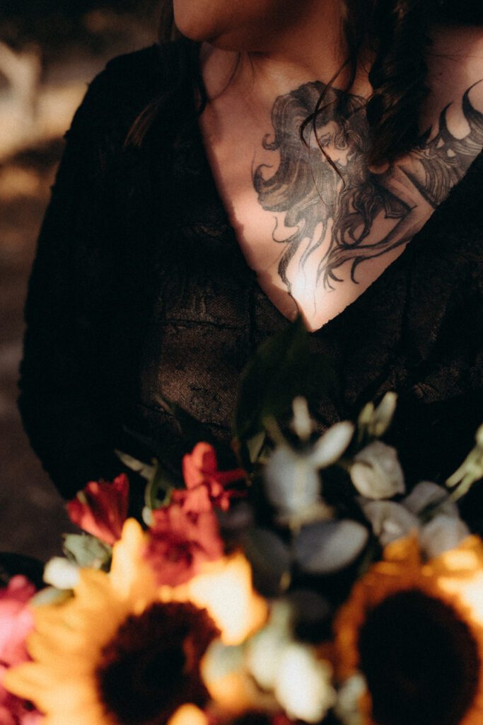 Tatouage de pieuvre sur la poitrine de la mariée, bouquet de tournesols et de fleurs rouges