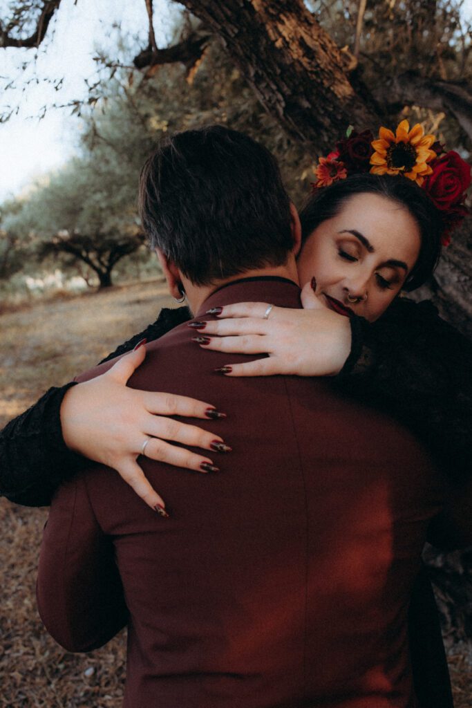 La mariée, couronne de fleurs rouges et tournesol, serre Marvin dans ses bras, yeux fermés