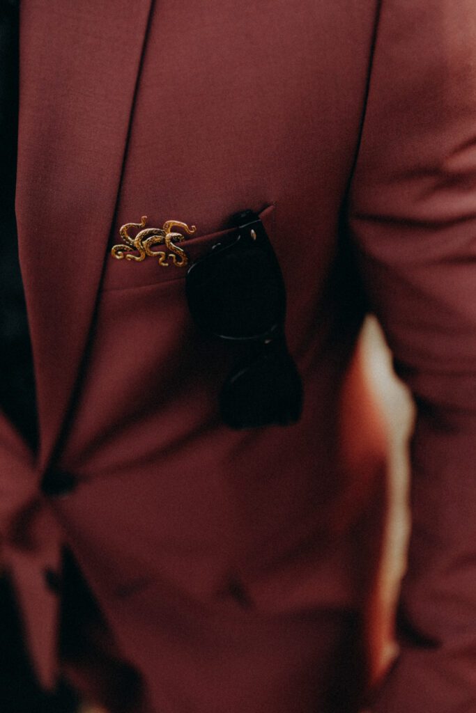 Pin’s doré en forme de pieuvre sur la poche de la veste bordeaux de Marvin