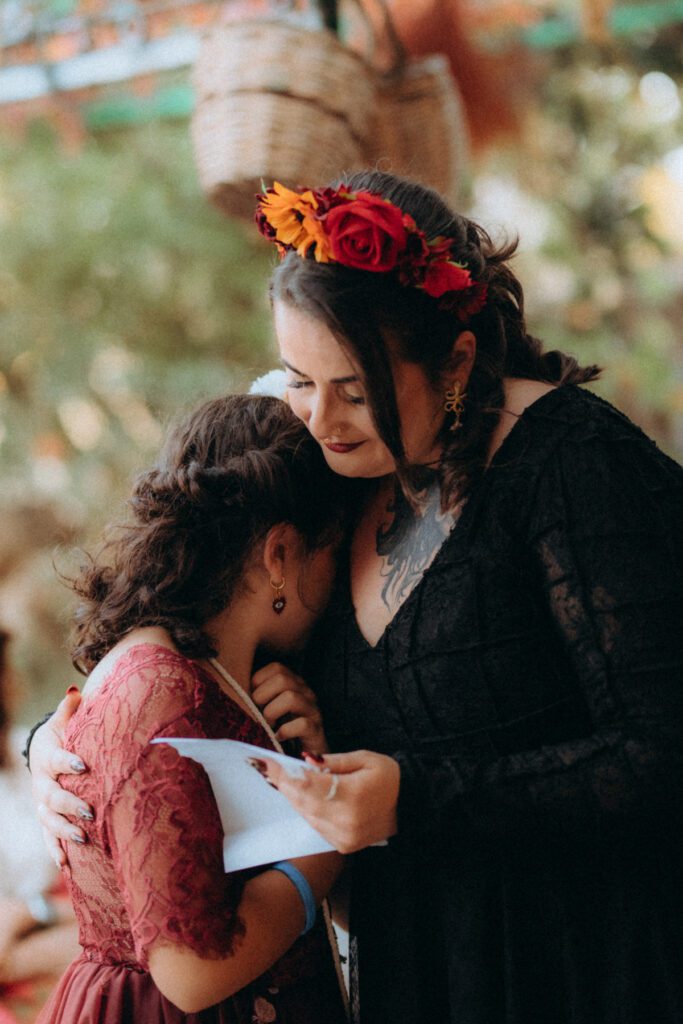 La mariée serre dans ses bras sa fille en robe rouge pendant la cérémonie lors d'une lecture de discours