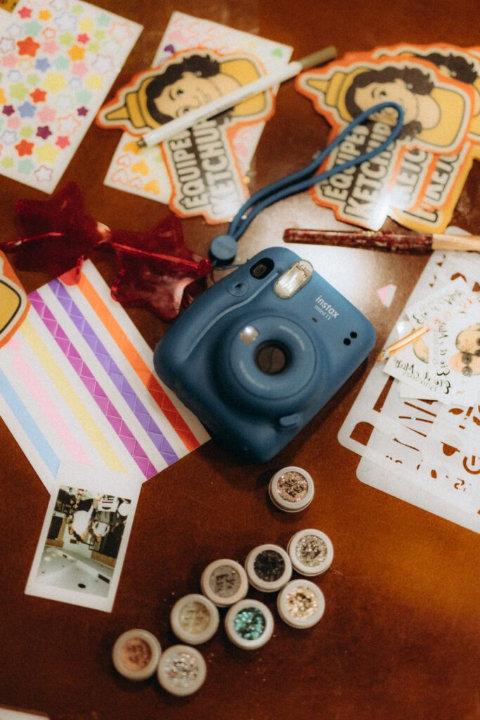 Appareil photo instantané bleu, autocollants et paillettes sur une table, jeux de la soirée de mariage