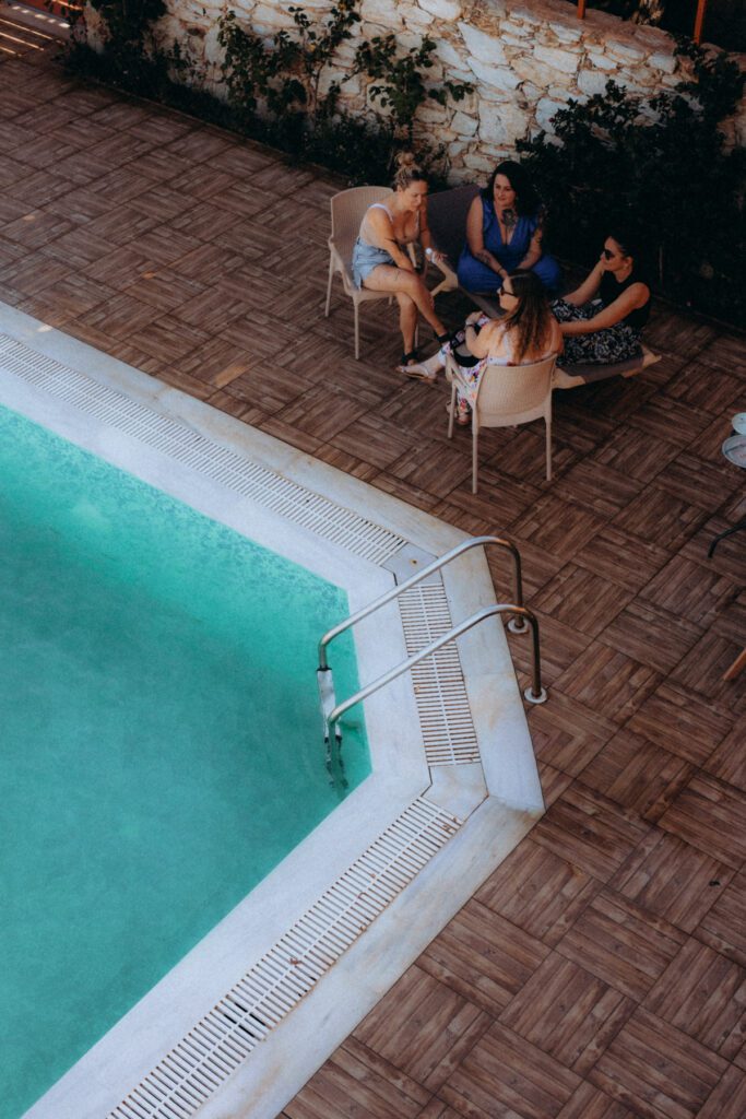 Vue plongeante sur la piscine de la villa en Crète, quelques invités assis au bord